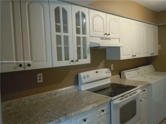 a utility room with stainless steel appliances granite countertop a stove and a sink