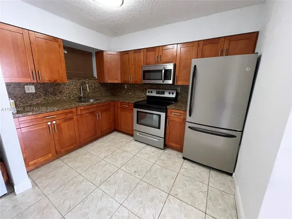 a kitchen with stainless steel appliances granite countertop a refrigerator stove a sink and a microwave