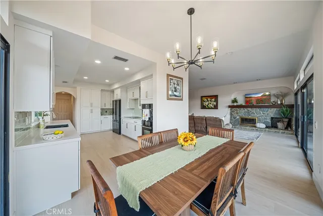 a view of a dining room and livingroom with furniture wooden floor a rug a fireplace and a chandelier