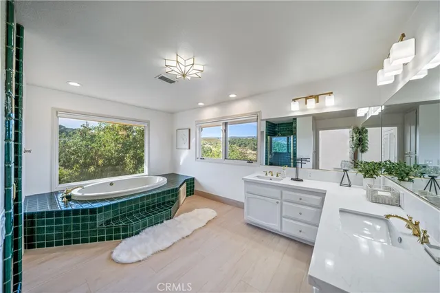 a spacious bathroom with a double vanity sink a large mirror and a bathtub