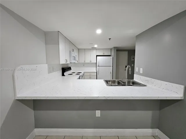 a view of kitchen with counter top space cabinets and refrigerator