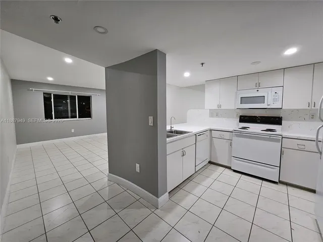 a kitchen with white cabinets a sink and white appliances