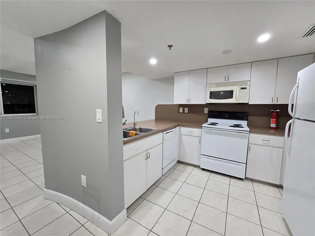 a kitchen with white cabinets a sink and white appliances