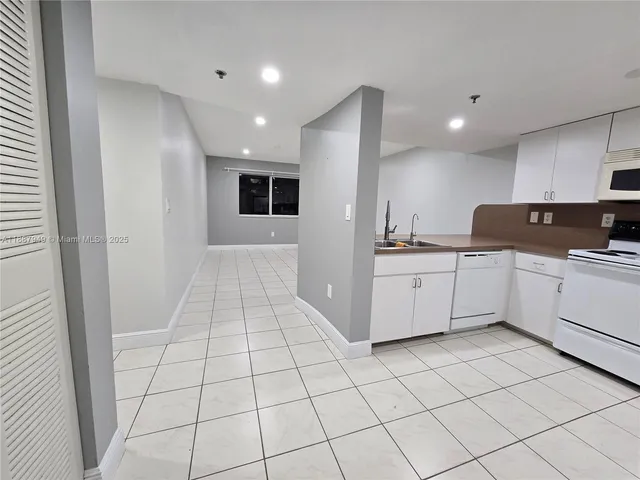 a large white kitchen with a sink and white cabinets