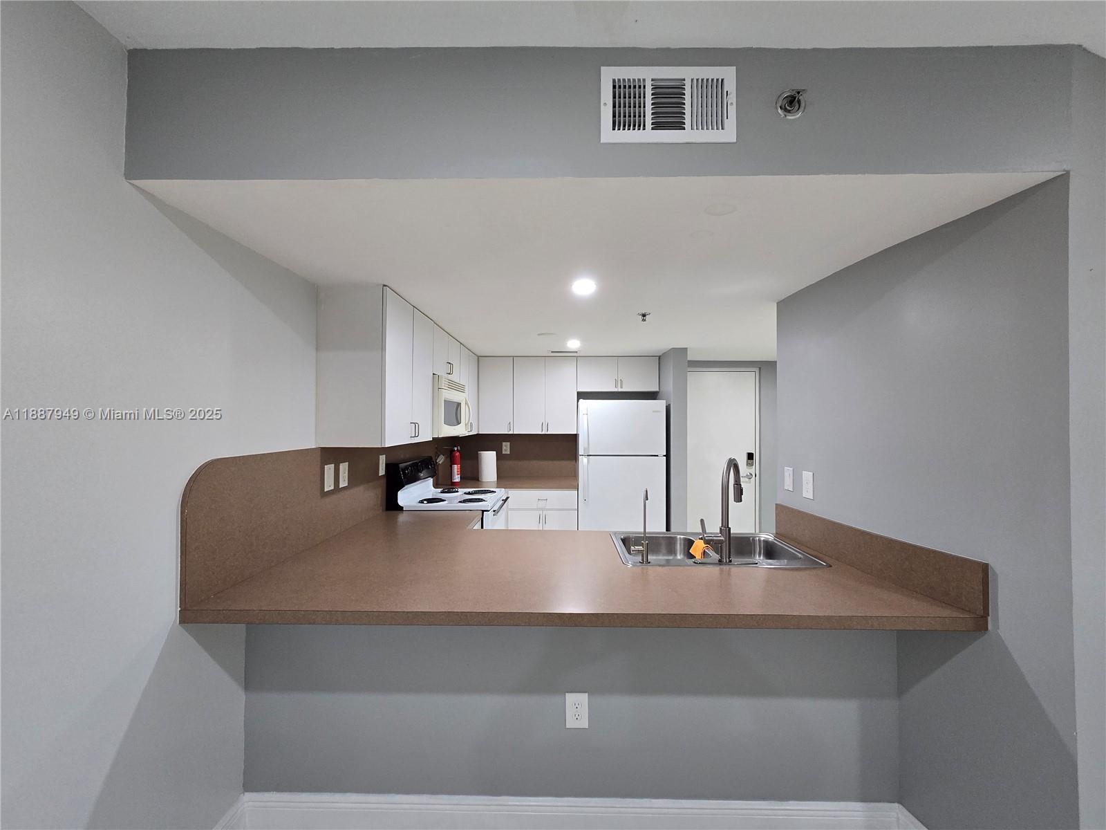 55 East 4th Street, Unit 302 Hialeah, FL 33010 - Photo 10 of 15 a view with kitchen island a sink a counter space and a refrigerator