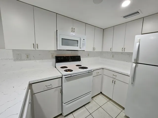 a kitchen with white cabinets and white appliances