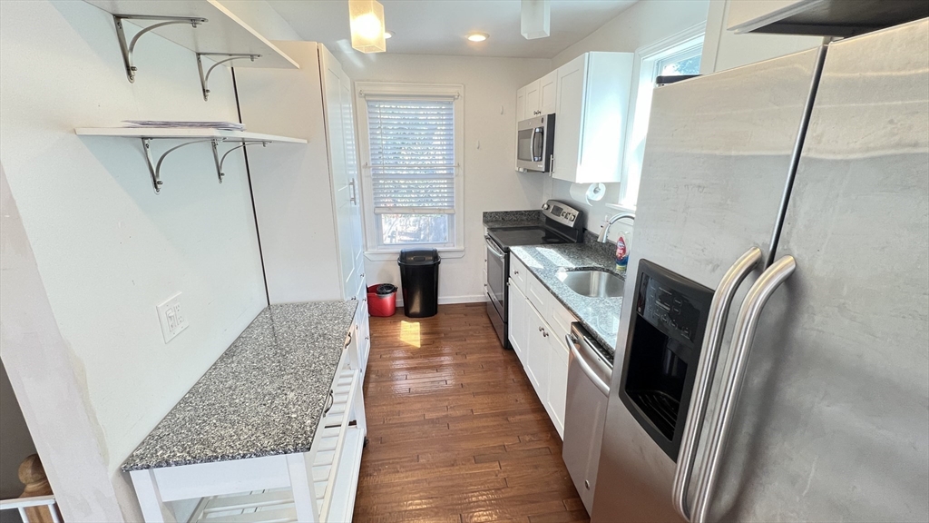 3 Mill St Court, Unit 2 Danvers, MA 01923 - Photo 2 of 23 a kitchen with kitchen island a counter top space a sink a refrigerator and washer