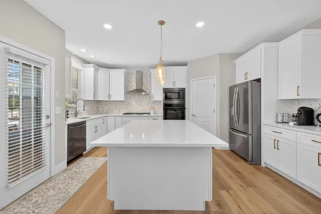 a large kitchen with stainless steel appliances kitchen island granite countertop a refrigerator a sink dishwasher a stove and a microwave oven with cabinets