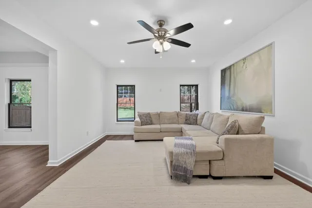 a view of empty room with wooden floor and fan