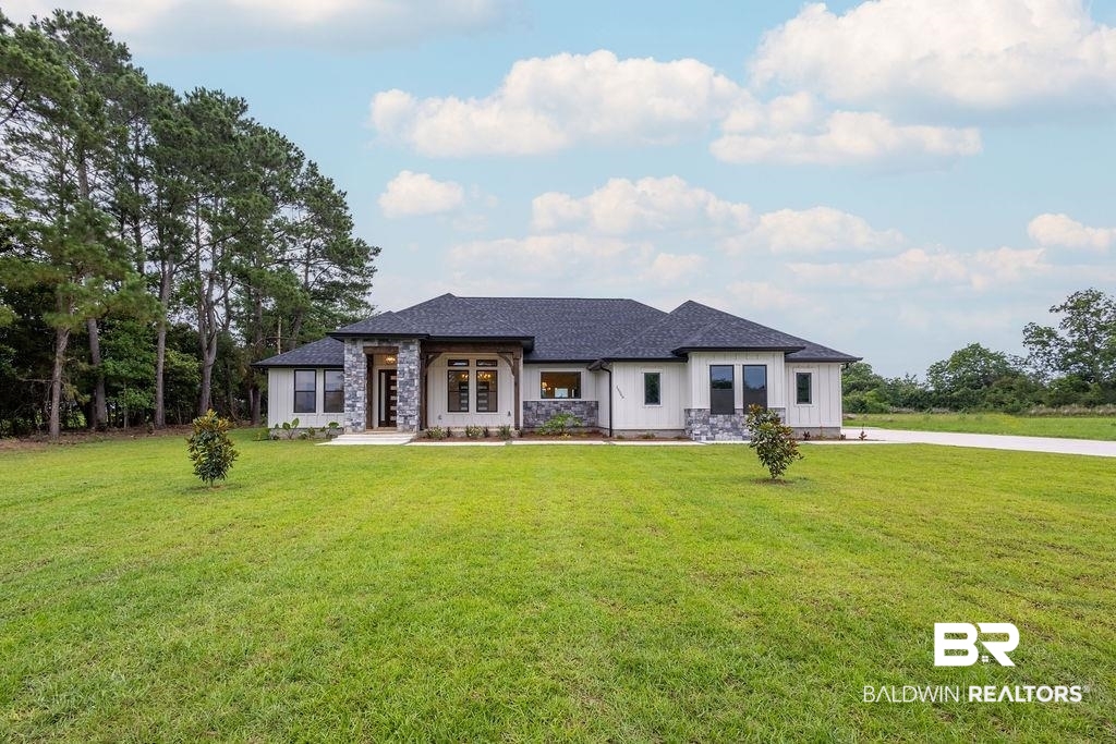 13066 Gopher Court Elberta, AL 36530 - Photo 1 of 38 Modern style custom home featuring a dark shingle roof, white board and batten siding, and beautiful stone accents.