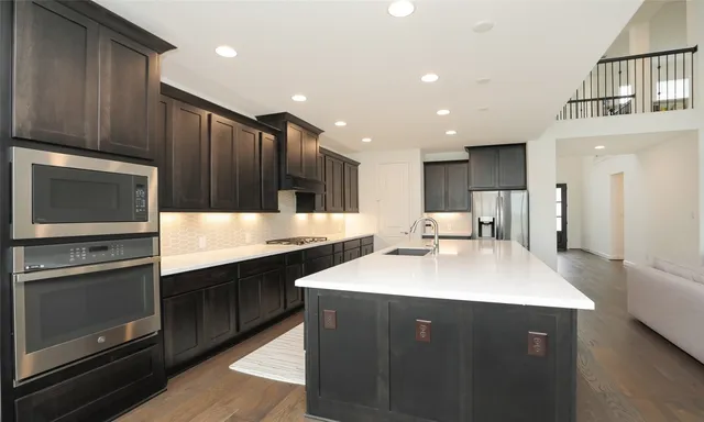 a large kitchen with stainless steel appliances kitchen island a large counter top and wooden floors