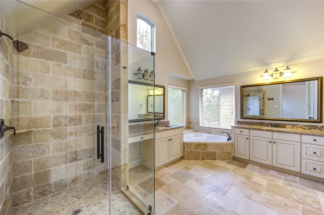 a large bathroom with a granite countertop double vanity sink a mirror and a bathtub