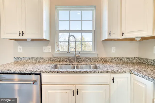 a kitchen with granite countertop white cabinets and a window