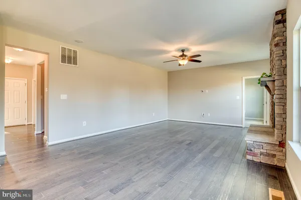 an empty room with wooden floor and ceiling fan