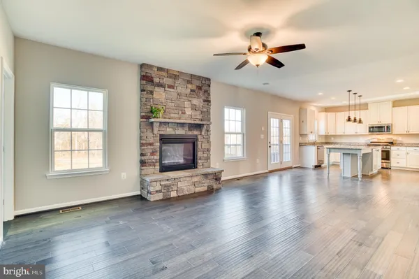 an empty room with wooden floor fireplace and windows