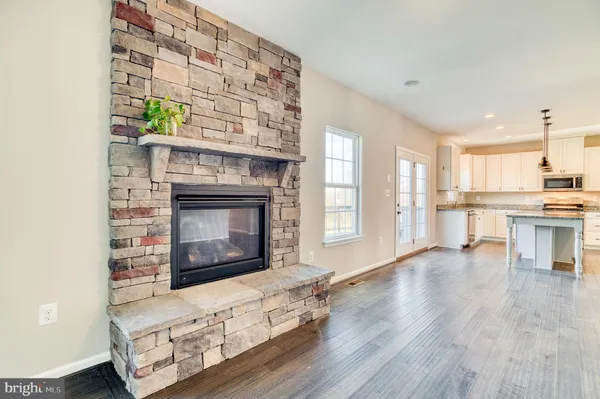 a living room with stainless steel appliances kitchen island granite countertop furniture and a fireplace