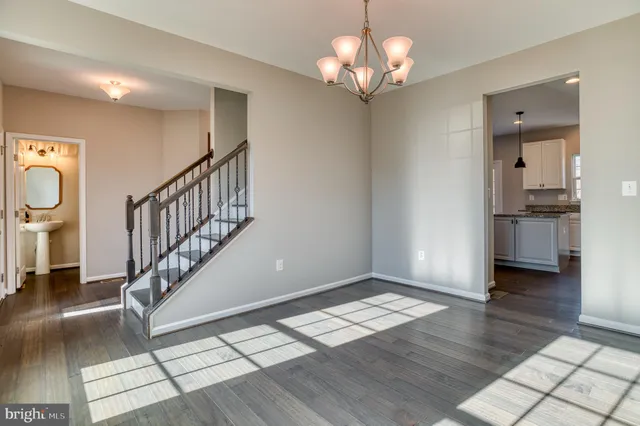 a view of empty room with wooden floor and pendant lights