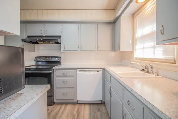 a kitchen with cabinets appliances a sink and a window