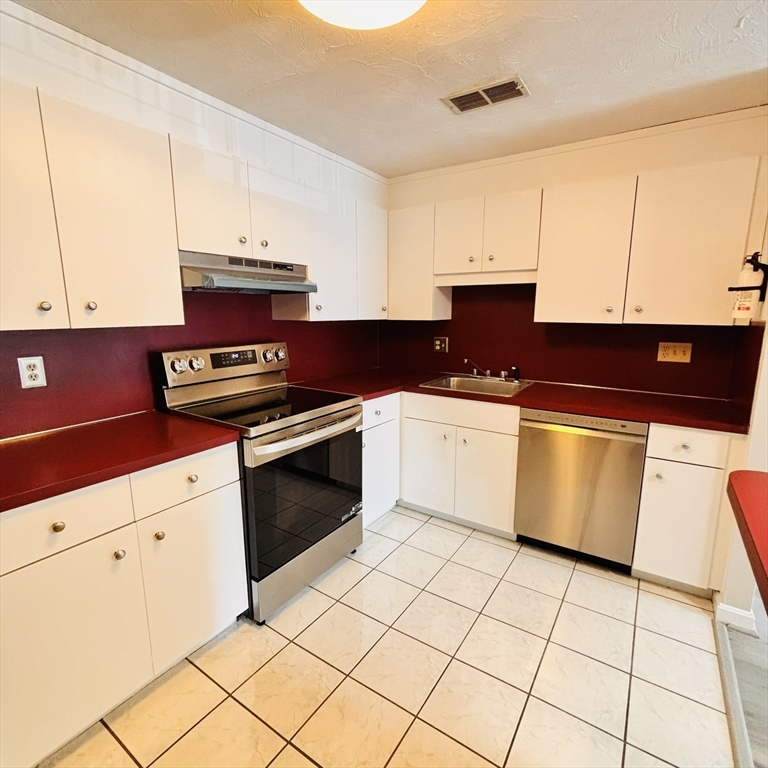 364 Neponset Street, Unit K Canton, MA 02021 - Photo 2 of 15 a kitchen with granite countertop a stove top oven sink and cabinets