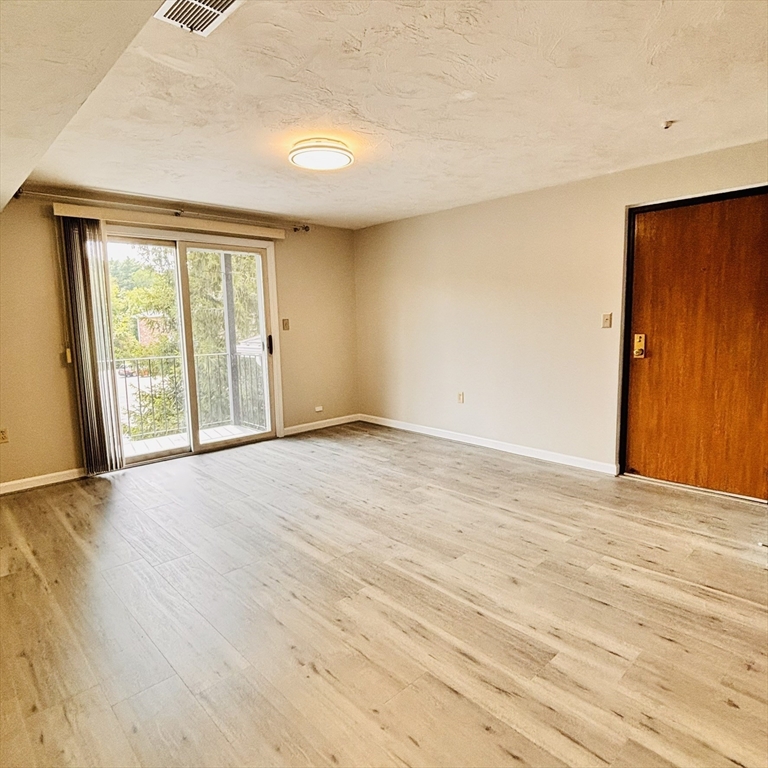 364 Neponset Street, Unit K Canton, MA 02021 - Photo 4 of 15 a view of an empty room with wooden floor and a window