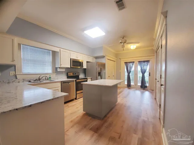 a large kitchen with a large counter top space a sink stainless steel appliances and cabinets