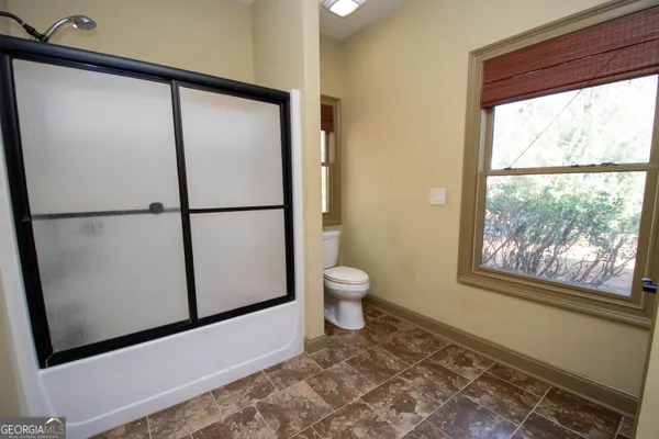 a view of a stone house with large trees