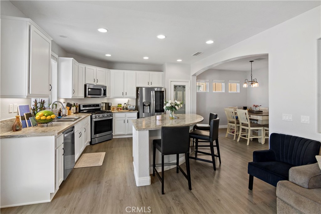 1664 Rigel Street Beaumont, CA 92223 - Photo 11 of 32 a kitchen with microwave a stove top oven a sink a dining table and chairs
