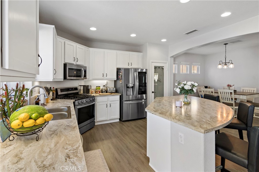 1664 Rigel Street Beaumont, CA 92223 - Photo 12 of 32 a kitchen with sink a refrigerator and chairs
