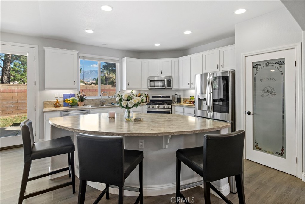 1664 Rigel Street Beaumont, CA 92223 - Photo 9 of 32 a kitchen with stainless steel appliances granite countertop a dining table chairs refrigerator and cabinets