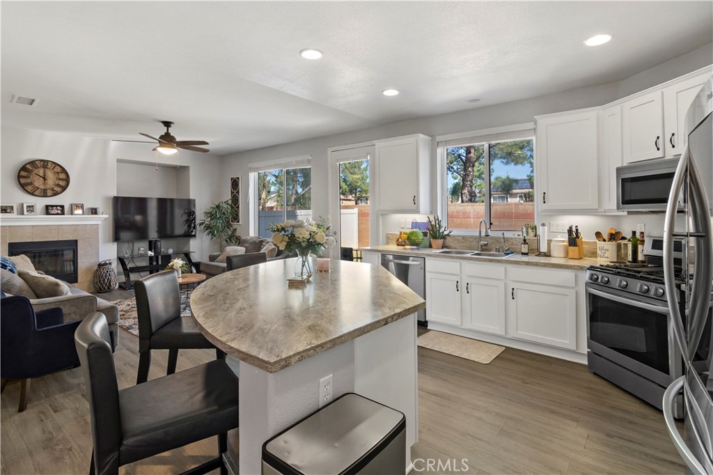 1664 Rigel Street Beaumont, CA 92223 - Photo 10 of 32 a open kitchen with stainless steel appliances granite countertop a stove a sink dishwasher a dining table and chairs with wooden floor