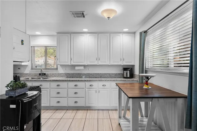 a kitchen with granite countertop a sink white cabinets and a stove