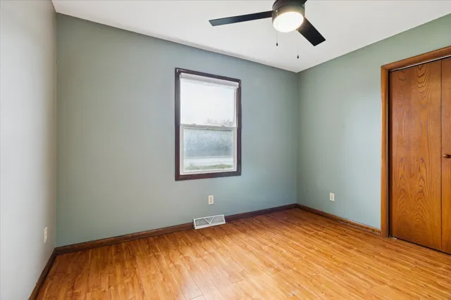 an empty room with a window and ceiling fan