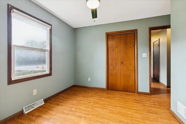 a view of an empty room with window and wooden floor