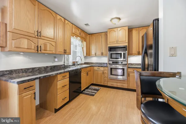 a kitchen with stainless steel appliances granite countertop a stove a sink dishwasher a microwave oven and a refrigerator with wooden floor