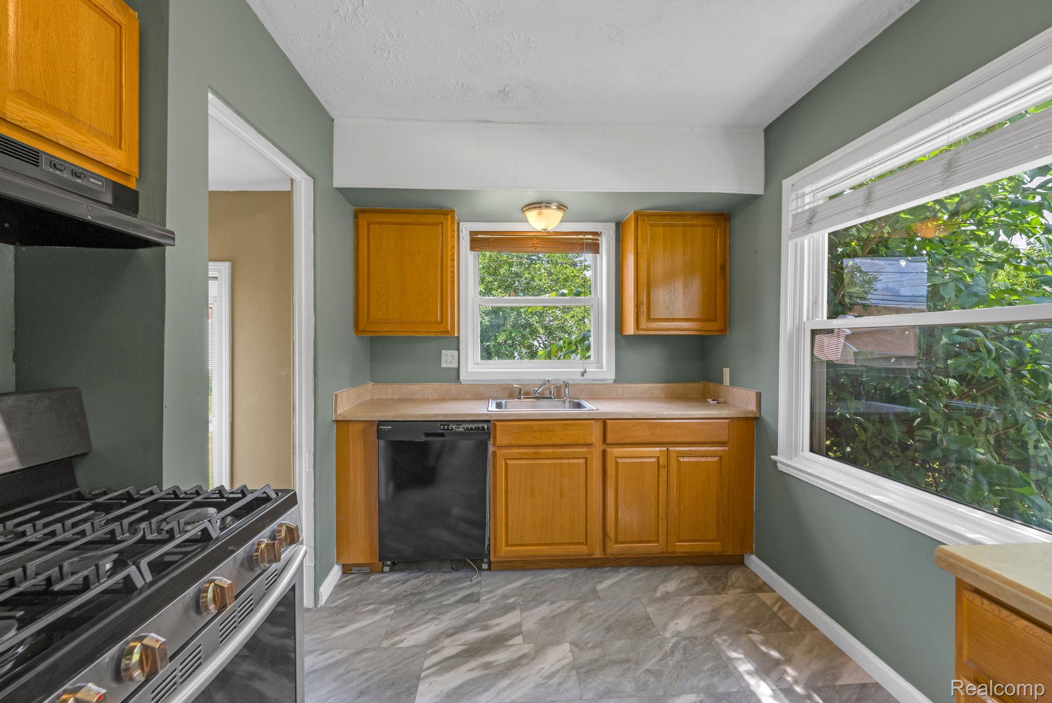 7641 Pelham Road Allen Park, MI 48101 - Photo 17 of 21 Kitchen featuring wood cabinetry, laminate countertops, a stainless steel gas range, a black dishwasher, and large windows