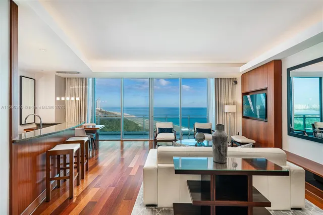 a living room with furniture a large window and wooden floor