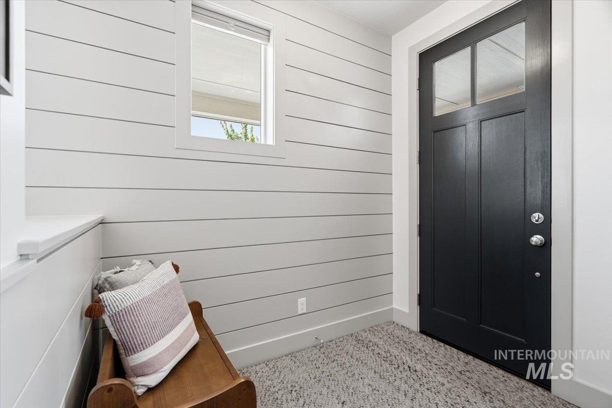 3794 South Single Tree Avenue Boise, ID 83716 - Photo 7 of 50 Entryway featuring a dark paneled door with upper glass inserts, shiplap wall detailing, a window with a roller shade, and a textured area rug