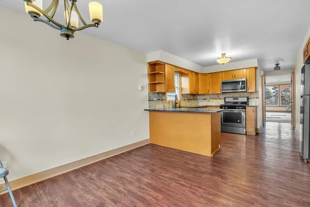 an open kitchen with wooden floor and stainless steel appliances