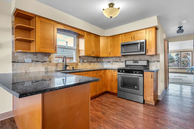 a kitchen with stainless steel appliances granite countertop a stove a sink and a microwave