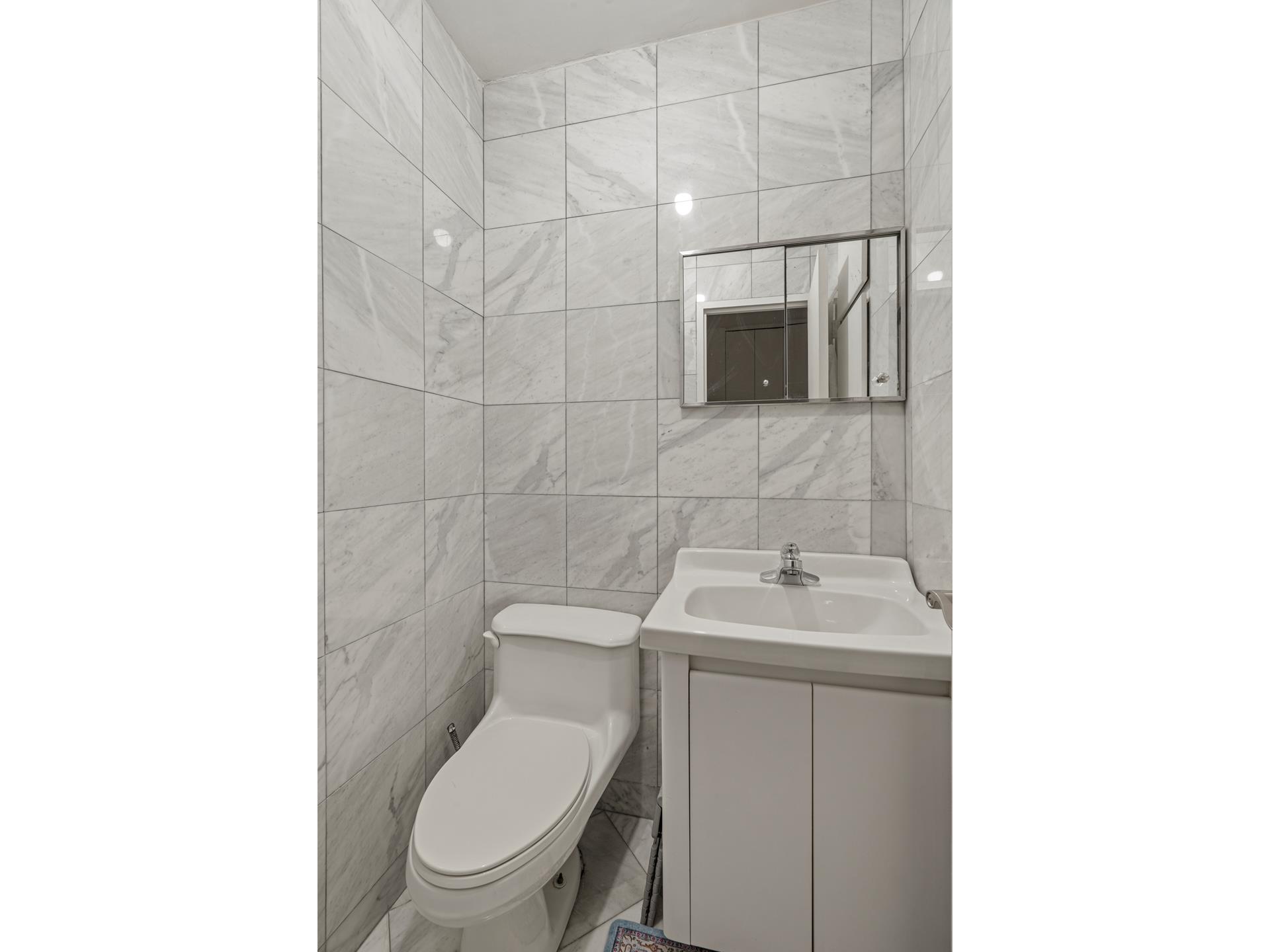 400 East 54th Street, Unit 14E Manhattan, NY 10022 - Photo 6 of 14 a bathroom with a toilet sink and mirror