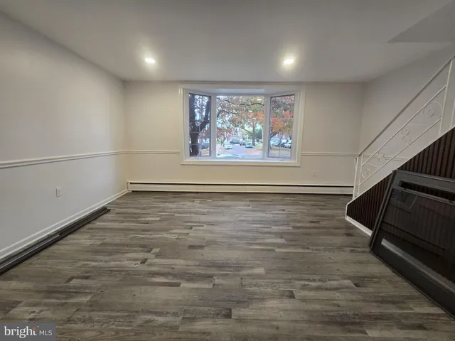 a view of an empty room with wooden floor and window