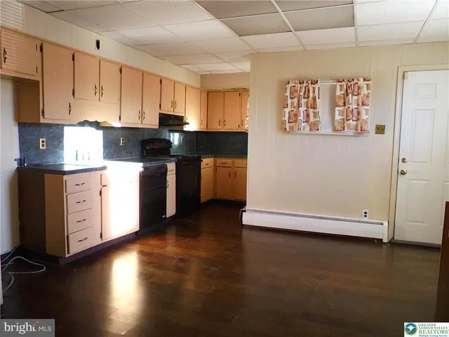 a kitchen with stainless steel appliances wooden floors and white walls