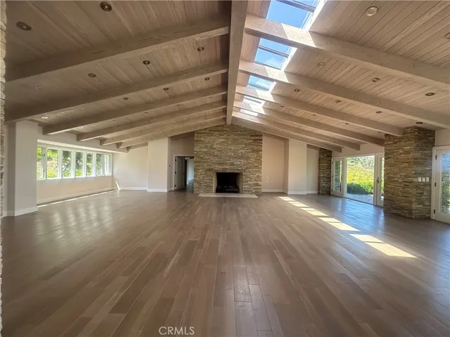a view of an empty room with wooden floor and a fireplace