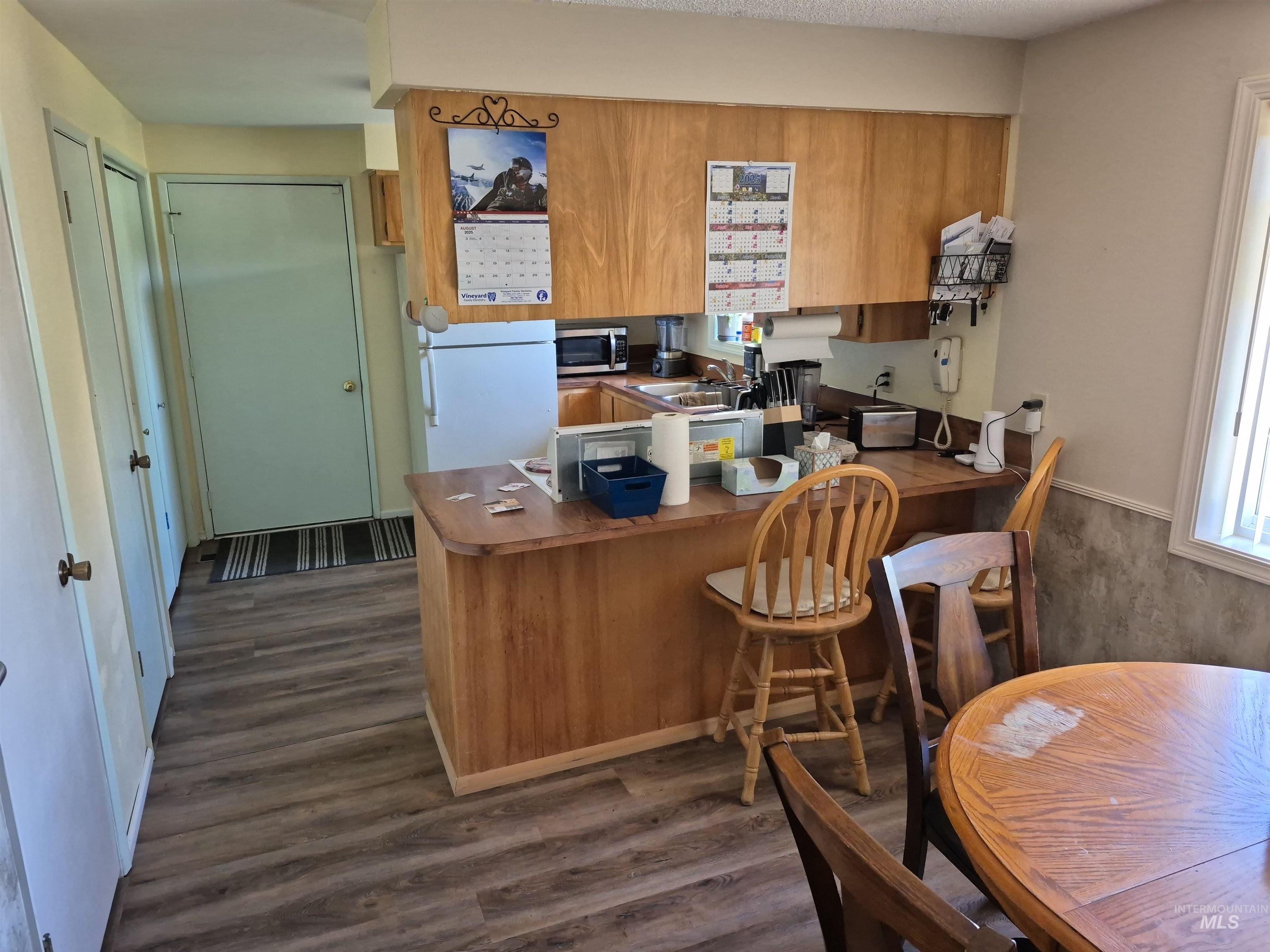 701 Wheeler Street Kendrick, ID 83537 - Photo 26 of 32 Kitchen featuring dark wood finished floors, a peninsula, freestanding refrigerator, and brown cabinets
