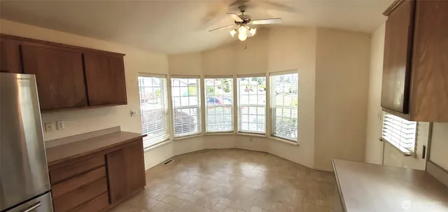 a view of an empty room with a window and a kitchen