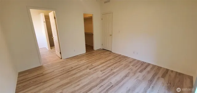 an empty room with wooden floor and a hallway