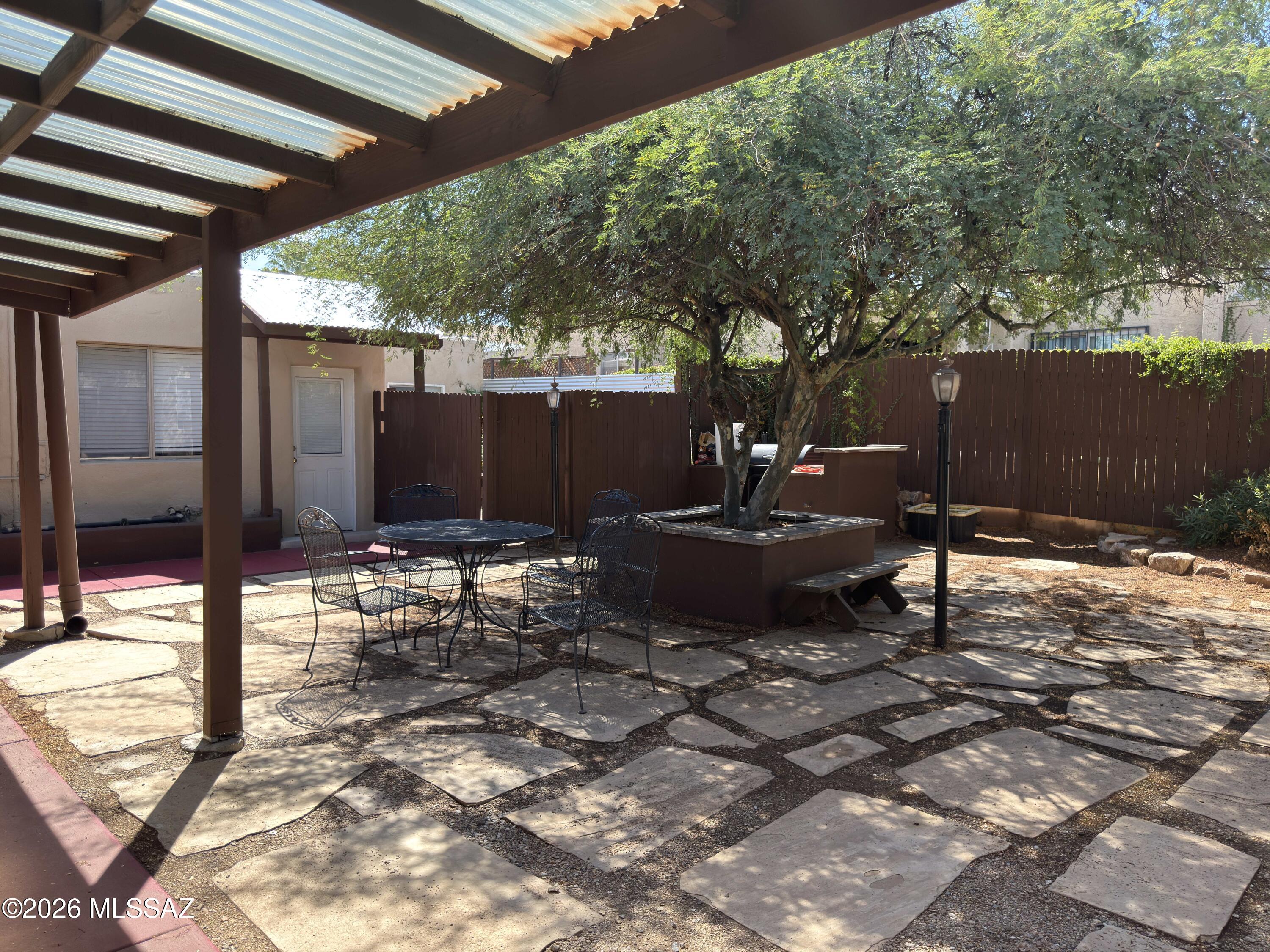 2619 East Prince Road Tucson, AZ 85716 - Photo 9 of 50 a view of a backyard with table and chairs potted plants and a large tree