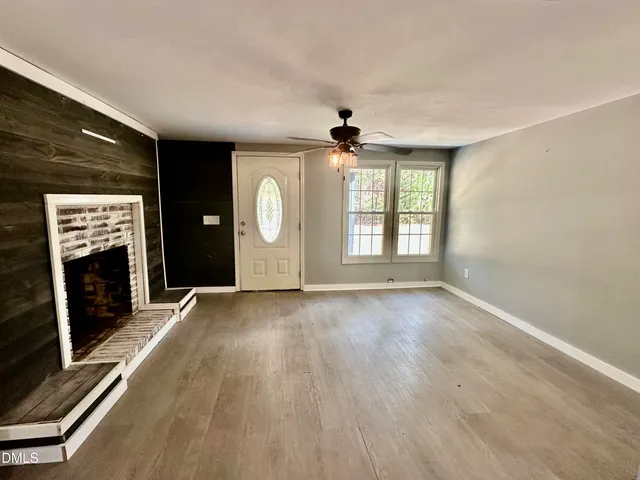 an empty room with windows fireplace and wooden floor