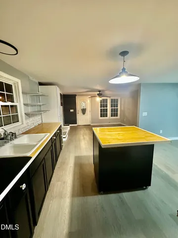 a view of a kitchen with kitchen island a sink and wooden floor