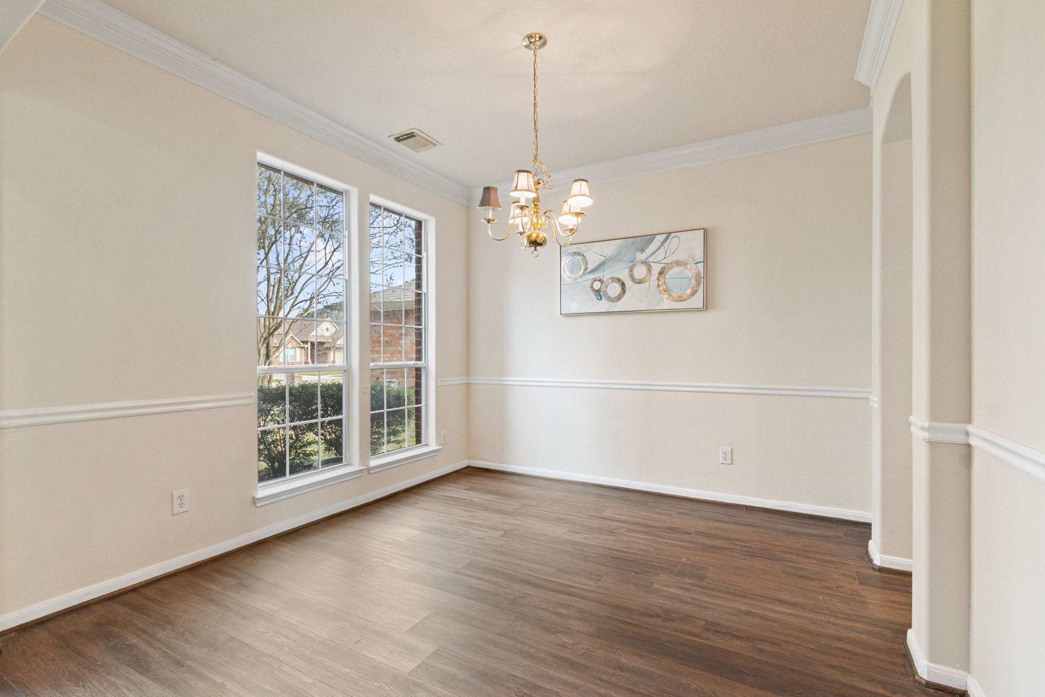 20907 Divellec Lane Spring, TX 77388 - Photo 8 of 50 Bright dining room with large windows, elegant chandelier, and hardwood floors. Features white walls with crown and chair rail molding.